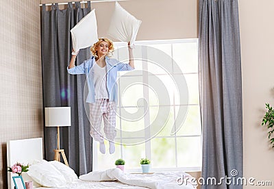 Happy young woman laughing and jumping on the bed in morning at home Stock Photo