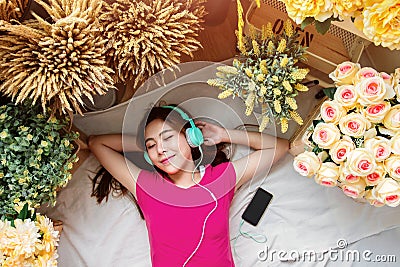 Happy Young Woman Laying on the Floor to Listening Music via Smart Phone, Closed Eyes and Smiling. Girl relaxing in Cozy Place, S Stock Photo