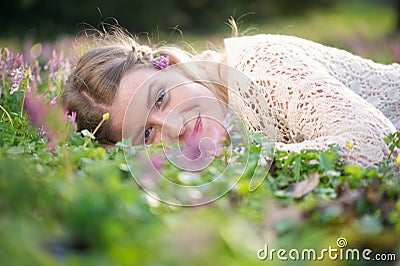 Happy young woman lying in grass and flowers Stock Photo