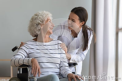 Happy young woman nurse carer help senior grandma on wheelchair Stock Photo