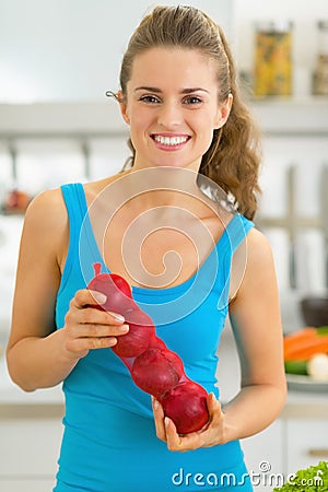 Happy young woman with onion in kitchen Stock Photo