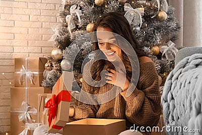 Happy young woman opening Christmas gift at home. Magic holiday Stock Photo