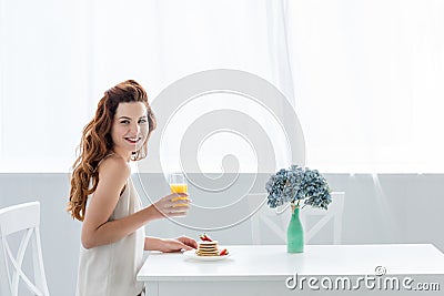 happy young woman with orange juice and pancakes with strawberry for breakfast looking Stock Photo