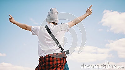 Happy young woman with outstretched hands enjoying sunny day. Bright blue sky with clouds in the background. Copy space Stock Photo