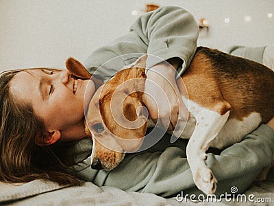 Happy young woman playing with her dog on a white background. Beagle dog with owner. Girl and dog at home Stock Photo