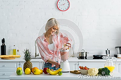 Young woman preparing tasty nutritious smoothie in blender Stock Photo