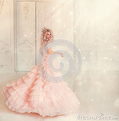 Happy young woman princess dancing in lush vintage pink dress. white royal room. Queen blond hair, golden crown. Stock Photo