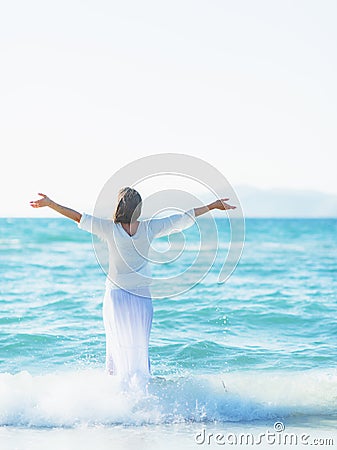 Happy young woman rejoicing on sea shore . rear view Stock Photo