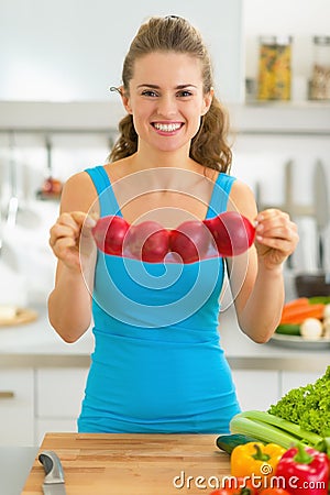 Happy young woman showing onion in kitchen Stock Photo