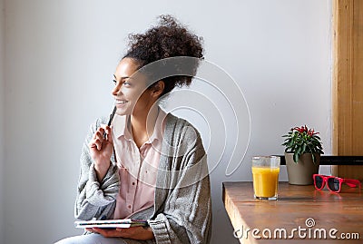 Happy young woman sitting at home with pen and paper Stock Photo