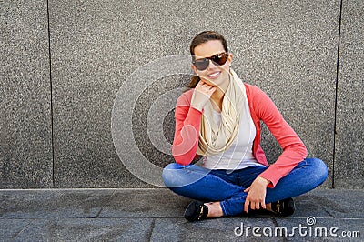 Happy young woman is smiling with a blank wall outside with sung Stock Photo