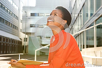 Happy young woman smiling with book and pen Stock Photo