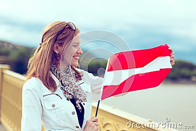 Happy young woman stretching Austrian flag on bridge Stock Photo