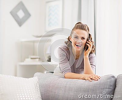 Happy young woman talking cell phone in living room Stock Photo