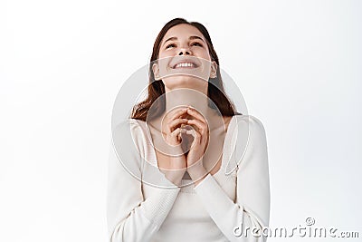 Happy young woman thanking god, looking relieved and joyful on top, saying prayer, express gratitude and delight, making Stock Photo