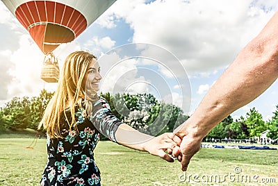 Happy young woman wants to make balloon tour holding boyfriend`s hand - Follow me, future together and love concept - Couple of Stock Photo