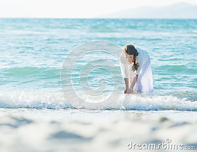 Happy young woman wetting hands in sea Stock Photo
