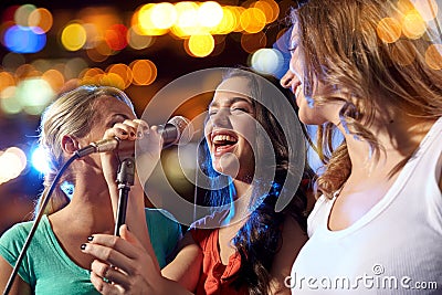 Happy young women singing karaoke in night club Stock Photo