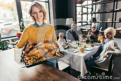 happy young woman with thanksgiving turkey for holiday dinner with family and looking Stock Photo