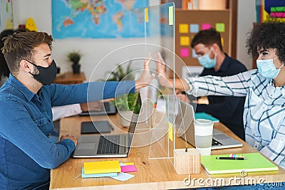 Happy young workers behind safety plexiglass at modern office - Focus on right man face Stock Photo