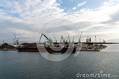 Harbor crane unloading scrap metal from a freight ship in the industrial port of Ploce Editorial Stock Photo