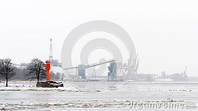Harbor landscape with red lighthouse and container cranes on a cold, foggy winter morning Stock Photo