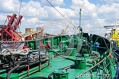 Harbor view with a closeup fragment of the green forward deck of a small ship Stock Photo