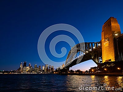 Harbour Bridge and Sydney city skyline at night against bright dark blue sky Stock Photo