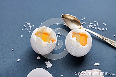 Hard-boiled eggs on a blue pastel background, half peeled, next to it are shells, salt and a spoon. The concept of a Stock Photo