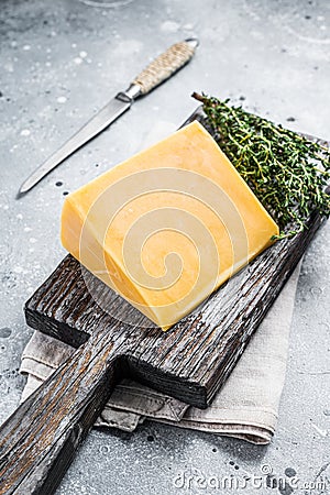 Hard cheese with knive on wooden cutting board. Parmesan. Gray background. Top view Stock Photo