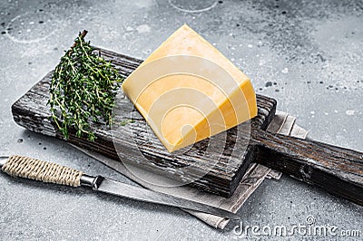 Hard cheese with knive on wooden cutting board. Parmesan. Gray background. Top view Stock Photo