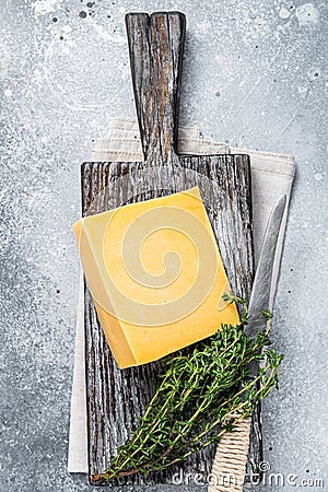 Hard cheese with knive on wooden cutting board. Parmesan. Gray background. Top view Stock Photo