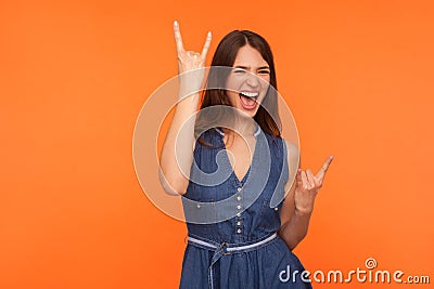 Hard rock lover. Delighted crazy brunette woman in denim dress making devil horns gesture with fingers up Stock Photo