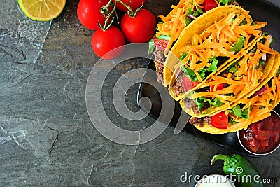 Hard shelled tacos with ground beef, vegetables and cheese, border on a dark background Stock Photo