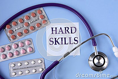 HARD SKILLS - words on a white piece of paper on a blue background. A stethoscope and pills lie side by side Stock Photo