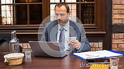 Hard working businessman in restaurant with laptop and mobile phone. Stock Photo