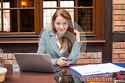 Hard working businesswoman in restaurant with laptop and mobile phone. Stock Photo