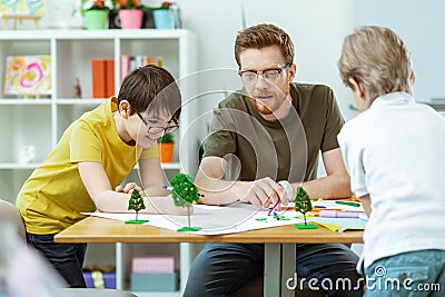 Smart bearded teacher pointing on pictures and explaining meaning Stock Photo