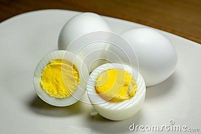 Hardboiled eggs with one cut in half on a plate at the kitchen table Stock Photo