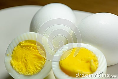 Hardboiled eggs with one cut in half on a plate at the kitchen table Stock Photo
