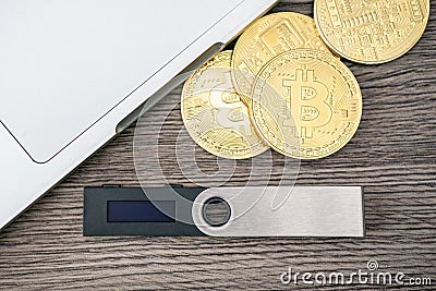 Hardware cryptocurrency wallet with golden Bitcoin BTC and computer. Safe storage for crypto Stock Photo