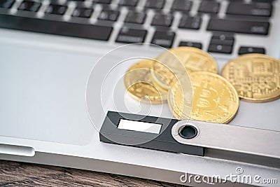 Hardware cryptocurrency wallet with golden Bitcoin BTC on computer. Safe storage for crypto Stock Photo