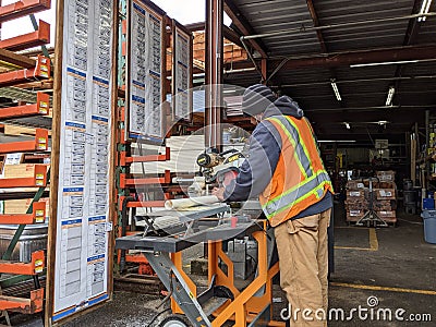 Woodinville, WA USA - circa March 2021: Hardware store worker cutting PVC pipe with a buzz saw in the lumber yard at a McLendon Editorial Stock Photo