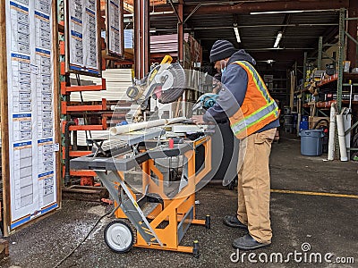Woodinville, WA USA - circa March 2021: Hardware store worker cutting PVC pipe with a buzz saw in the lumber yard at a McLendon Editorial Stock Photo