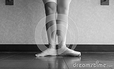 The hardworking disciplined ballerina ballet dancer warming up in her pointe shoes and bare feet, displaying the behind the scenes Stock Photo