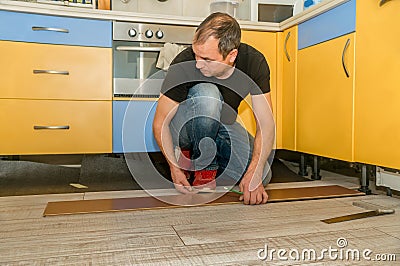 Hardworking man with a physical handicap in his hand that has several amputated fingers working on laying the floor of his house. Stock Photo