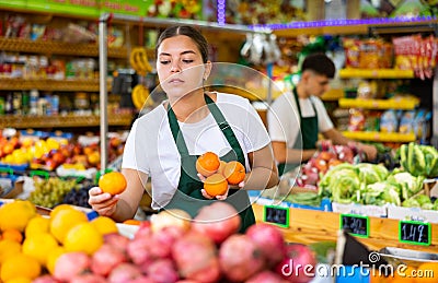 Hardworking young saleswoman puts fresh oranges on the counter Stock Photo