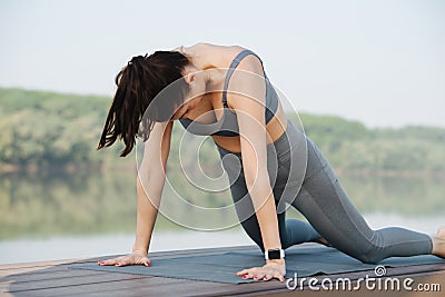 Hardy woman doing yoga outdoors in a beautiful spot on a riverside Stock Photo
