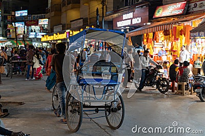 Rickshaw driver walks his vehicle through the crowded night market Editorial Stock Photo