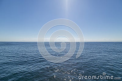 Harsh bright midday sun shining down on calm sparkling ocean Stock Photo